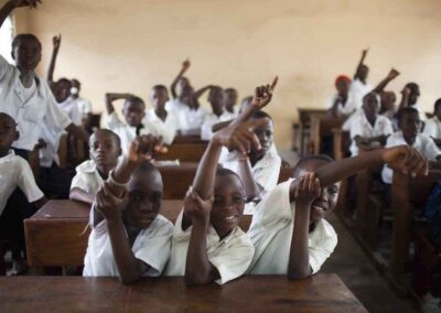 Boys in a classroom with their hands up