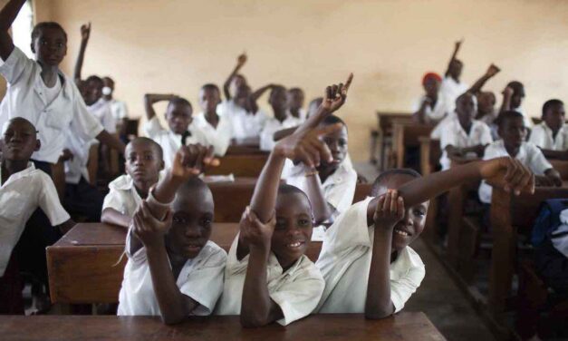 Boys in a classroom with their hands up