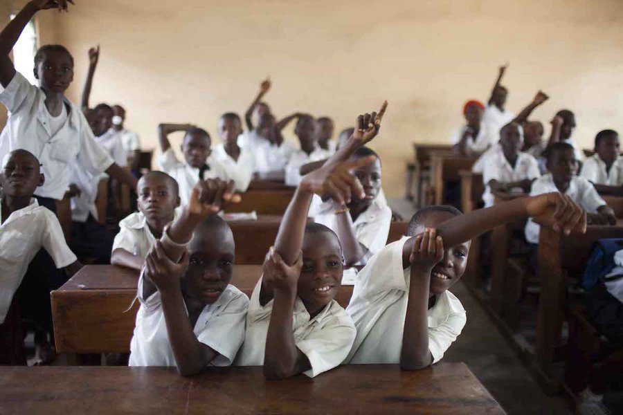 Boys in a classroom with their hands up