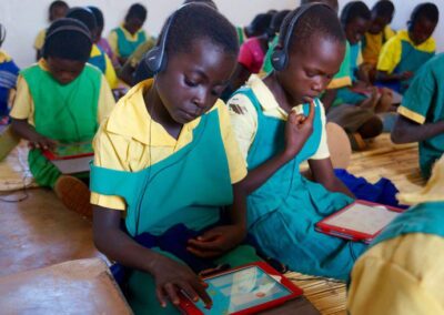 Children in class with headphones working on tablets