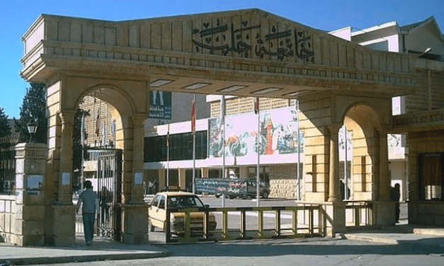 University of Aleppo - Archway with barriers and car and flagpoles beyond