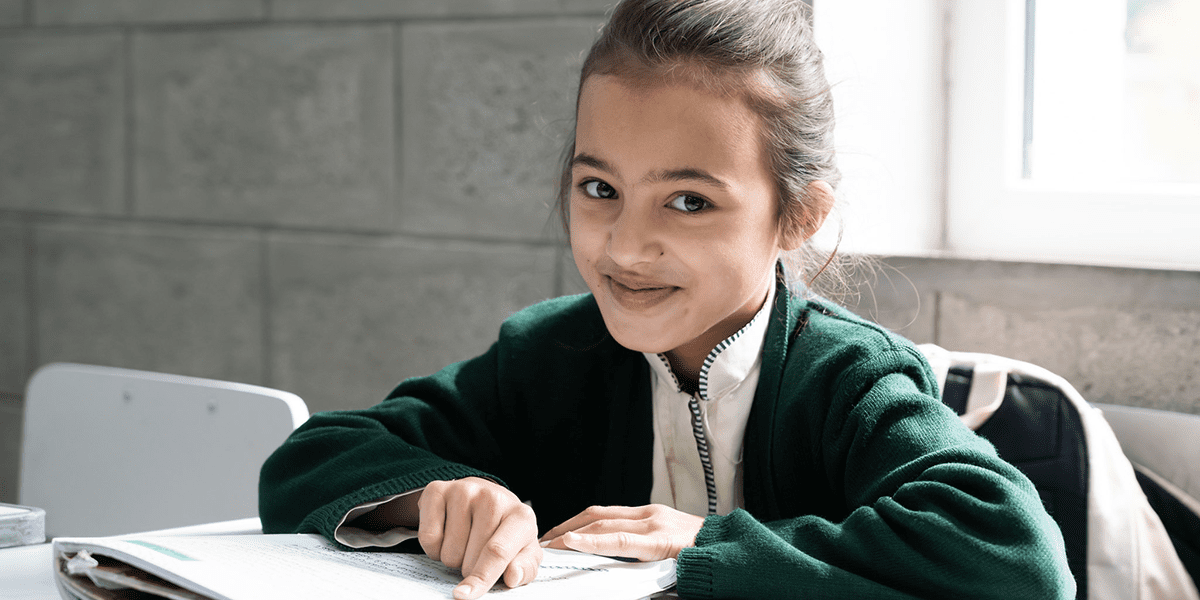 A girl in green uniform with a book on the desk