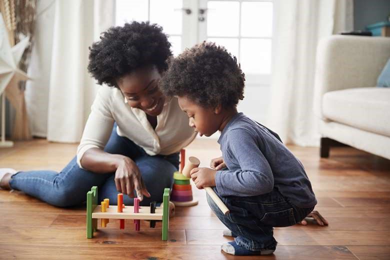 Mother and child playing with peg and hammer toy