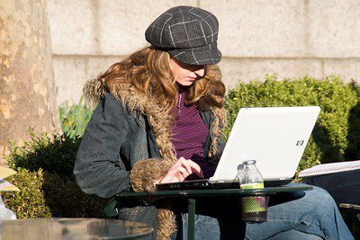 Woman sitting on a park bench with a laptop 