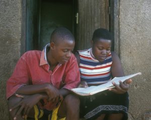 Teenage girl and boy in Uganda, looking at text book