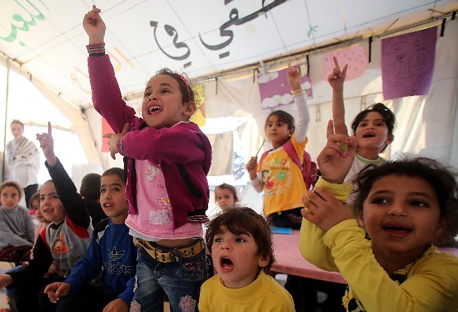 A group of children in a class holding up their hands