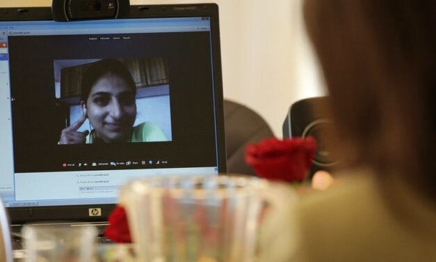 someone looking at a laptop with a video call displayed