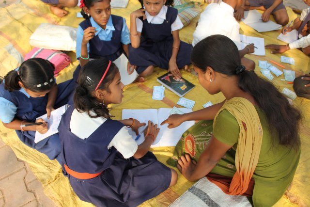 A group of Indian School children working on a yellow floor covering