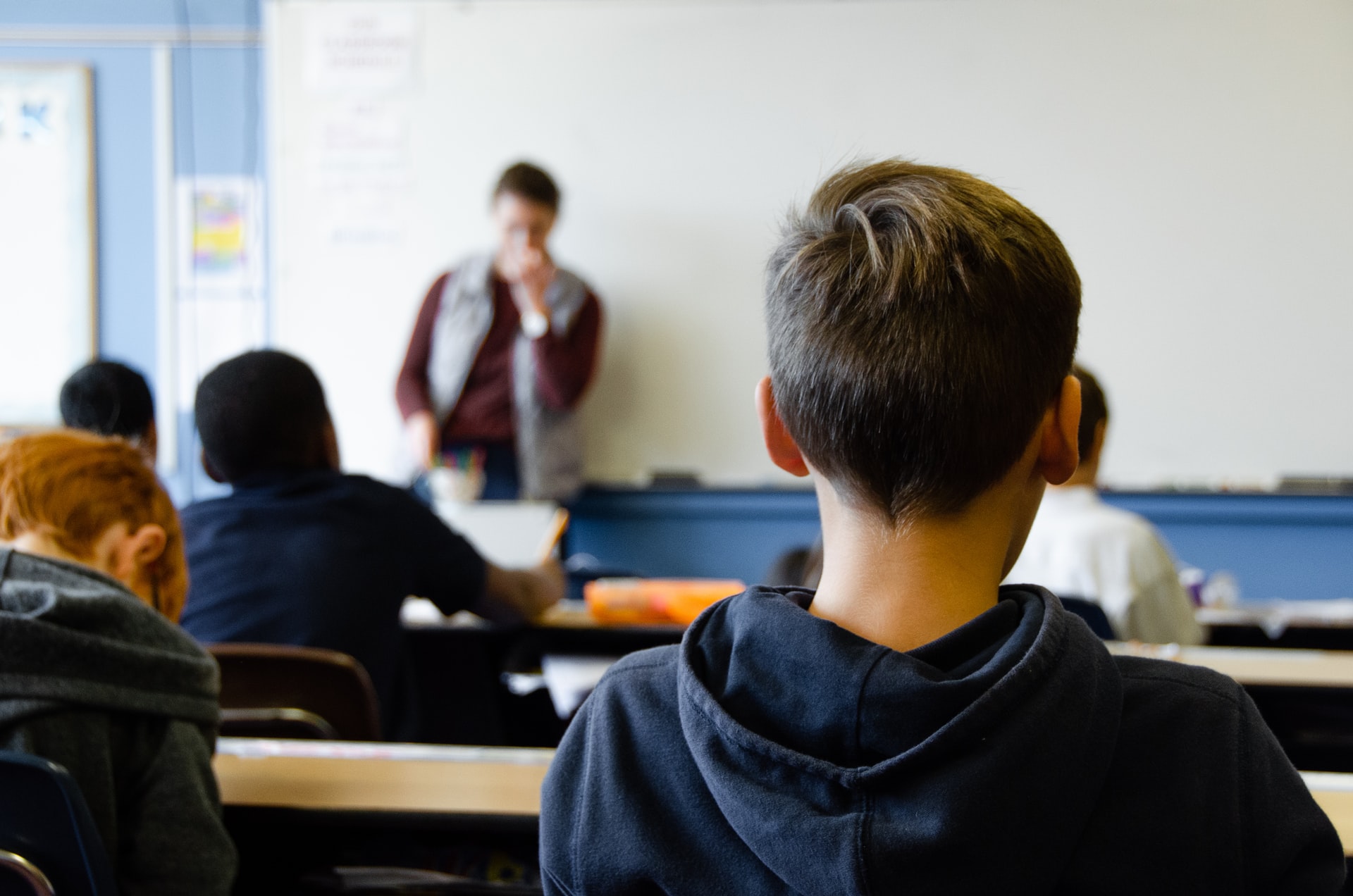 back view of pupil in western classroom with teacher at the front