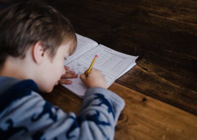 Child sitting at desk working on a workbook with a pencil