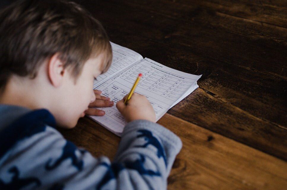 Child sitting at desk working on a workbook with a pencil