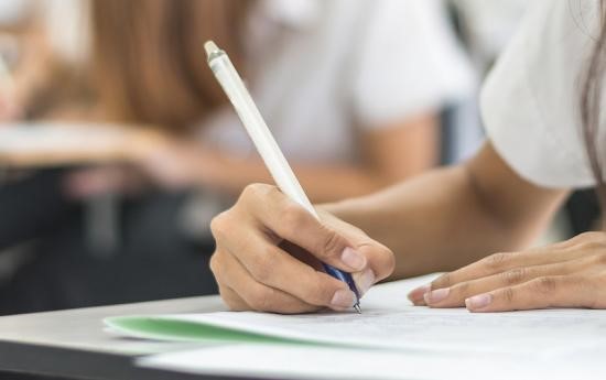 student's hands on work holding a pencil