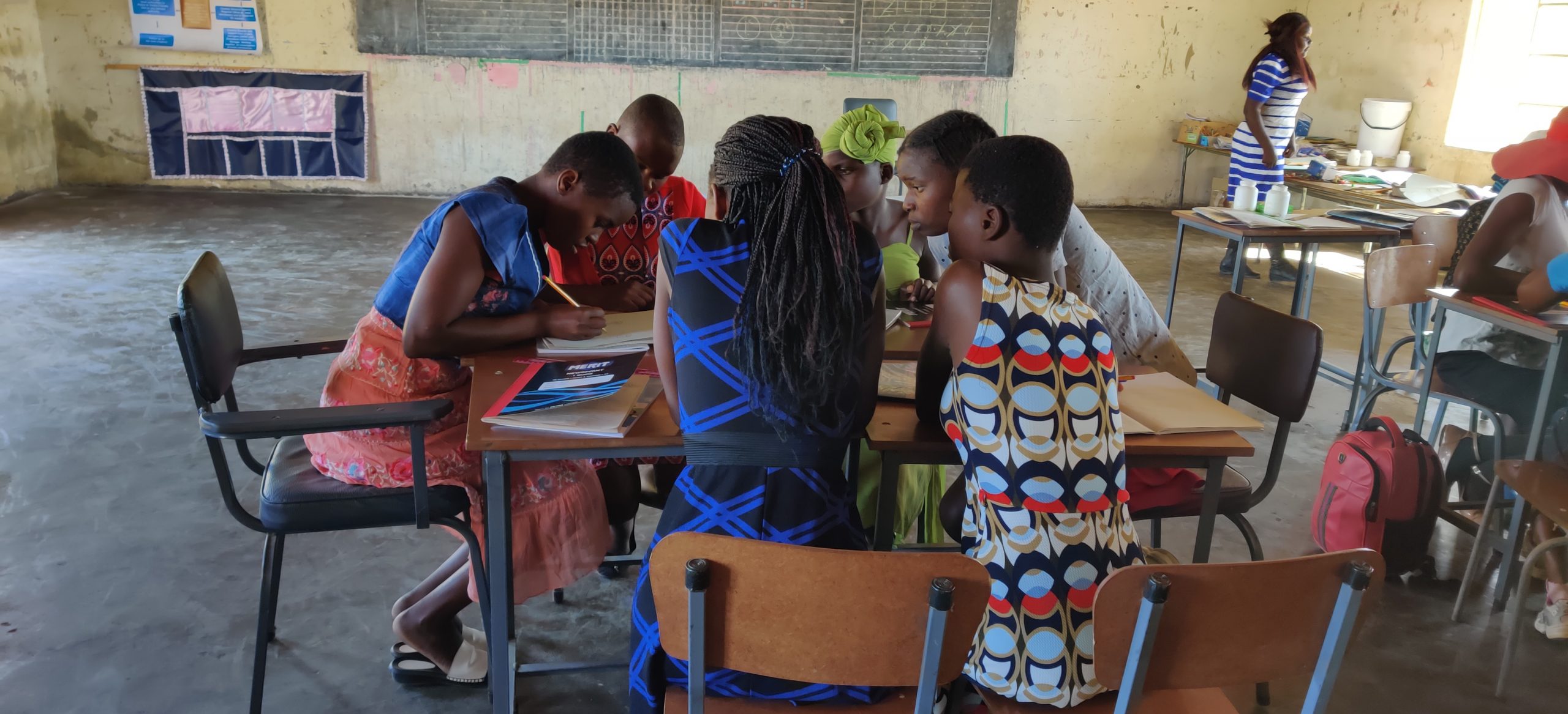 A group of African students grouped around a table working in a classroom