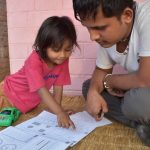 Adult male with a child looking at a school book