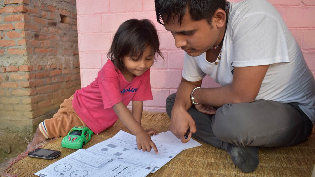 Adult male with a child looking at a school book