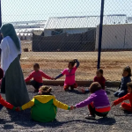 Adult and children playing in a refugee camp