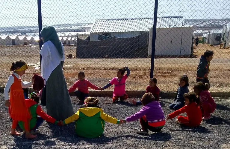 Adult and children playing in a refugee camp