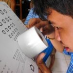 Cambodian child with magnifier taking a low vision assessment