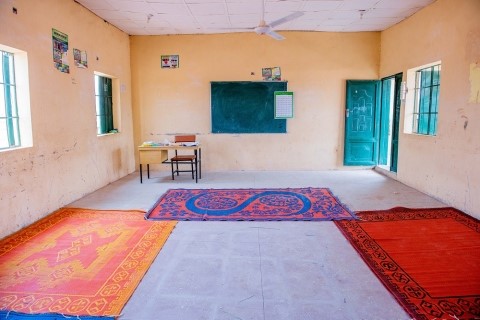 An empty classroom with coloured rugs on the floor