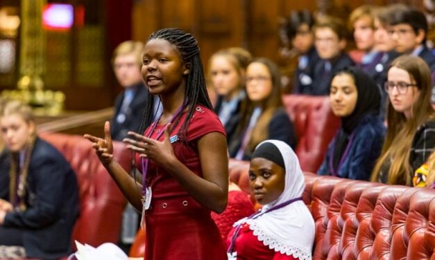 Young black woman standing and speaking among other school children