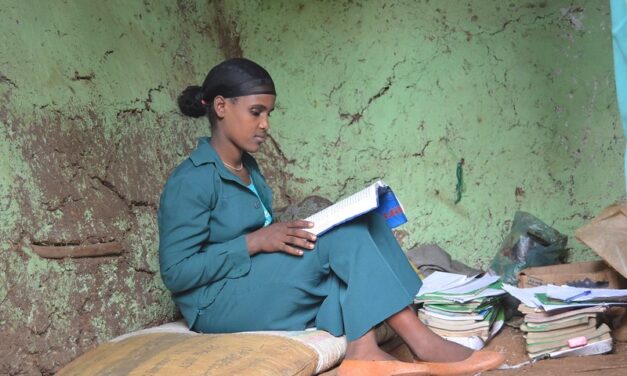 An Ethiopian grade 9 female student reading with a pile of books