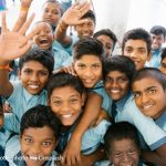 A group of Indian school boys smiling and waving