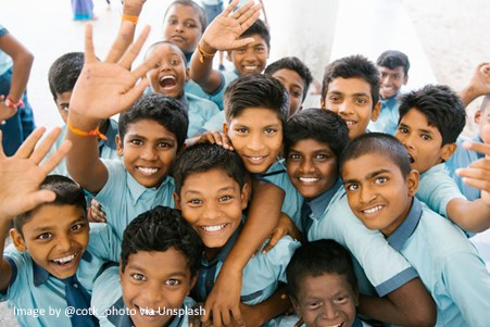 A group of Indian school boys smiling and waving