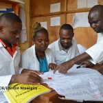 Rwandan mentor and teachers looking at learning materials