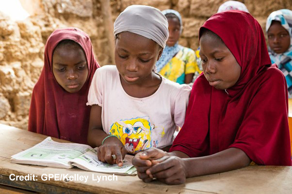 Three Girls looking at a book in a classroom in Niger