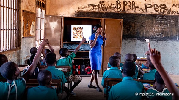 teacher in classroom with students with their hands up