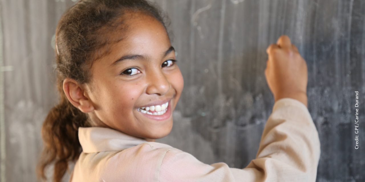 Smiling girl wriiting on a blackboard