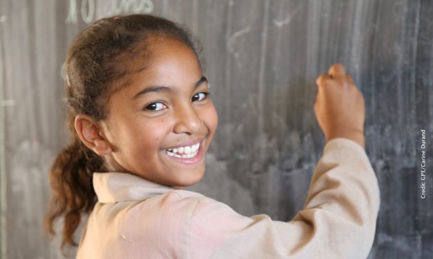 Smiling girl wriiting on a blackboard