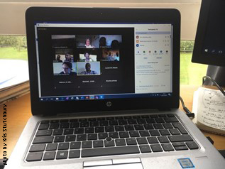 Open laptop on table, with screen showing participants of a zoom call