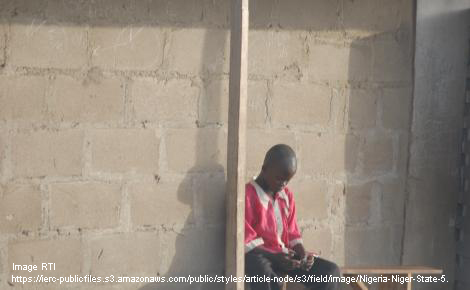 Nigerian boy sitting outside a building