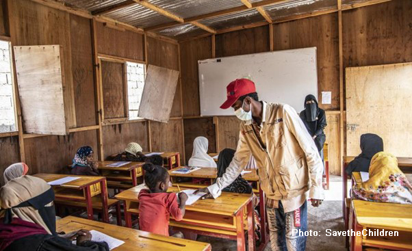 Masked teacher working with children in class