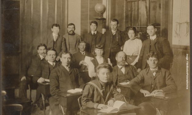 a sepia tinted photograph of students in period dress with women students among them