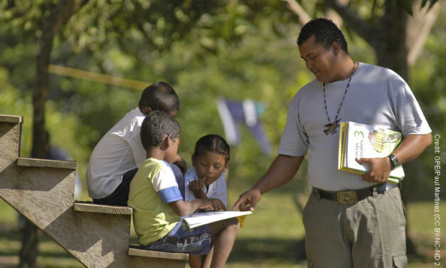 Teacher and student with book under a tree