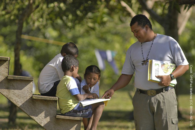 Teacher and student with book under a tree