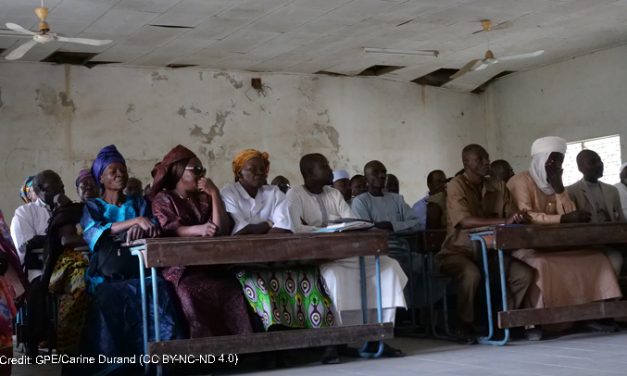 Adults sittiing in a row behind desks