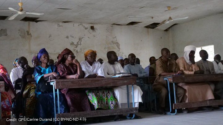 Adults sittiing in a row behind desks