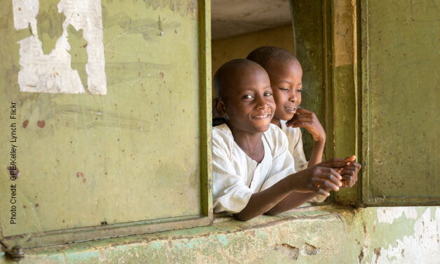 Two Boys looking out of a window smiling