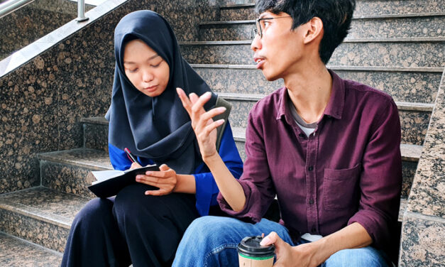 Two adult students in discussionm  sitting on steps 