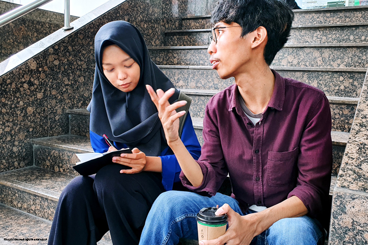 Two adult students in discussionm  sitting on steps 