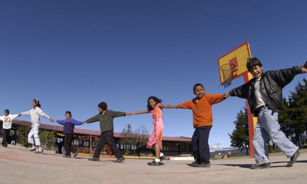 Children holding hands with their arm outstretched in a line