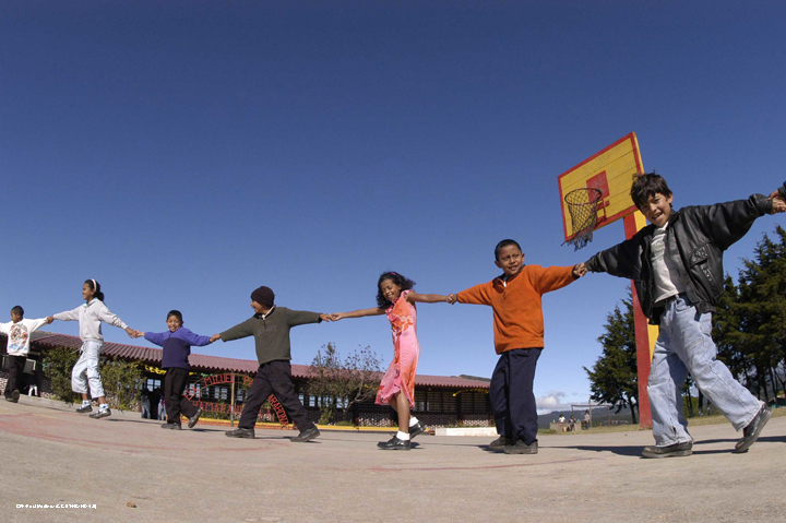 Children holding hands with their arm outstretched in a line