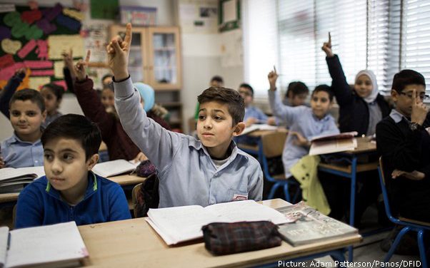 Children with their hands up in class in middle east school