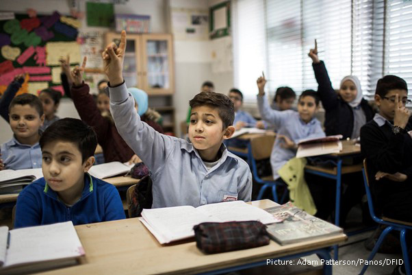 Children with their hands up in class in middle east school