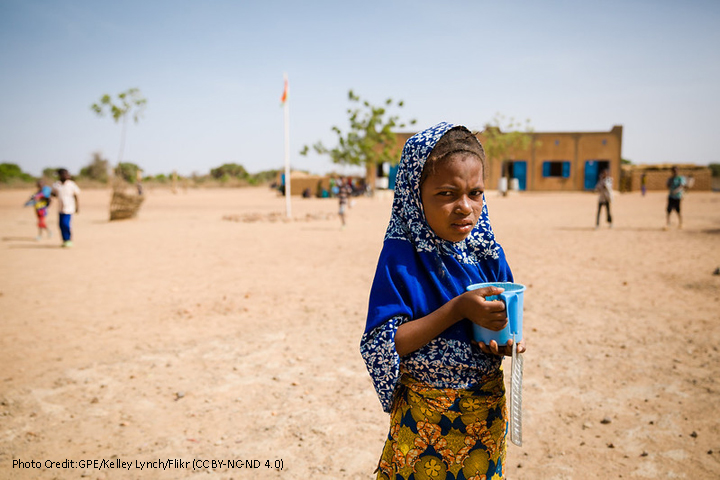 Girl with a cup outside a school building