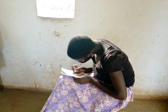 girl sitting writing, she is wearing a facemask