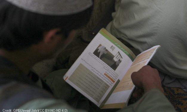 An Afghan boy reading a text book
